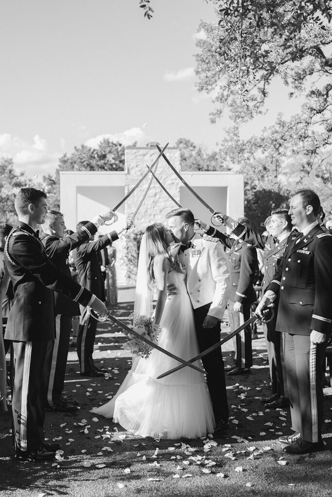 Bride and groom kiss at the last pair of sabers at military wedding