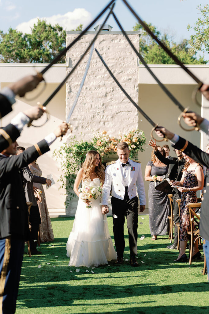 Bride and groom at their military wedding walking under the saber arch