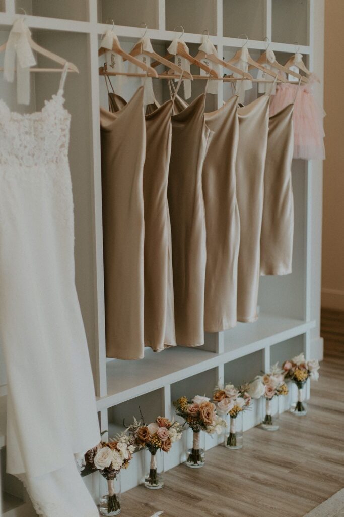 champagne satin bridesmaid dresses hanging next to wedding gown