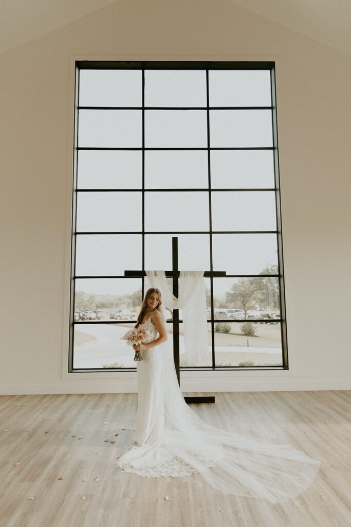 bride posing in front of ceremony back drop on her romantic summer wedding day