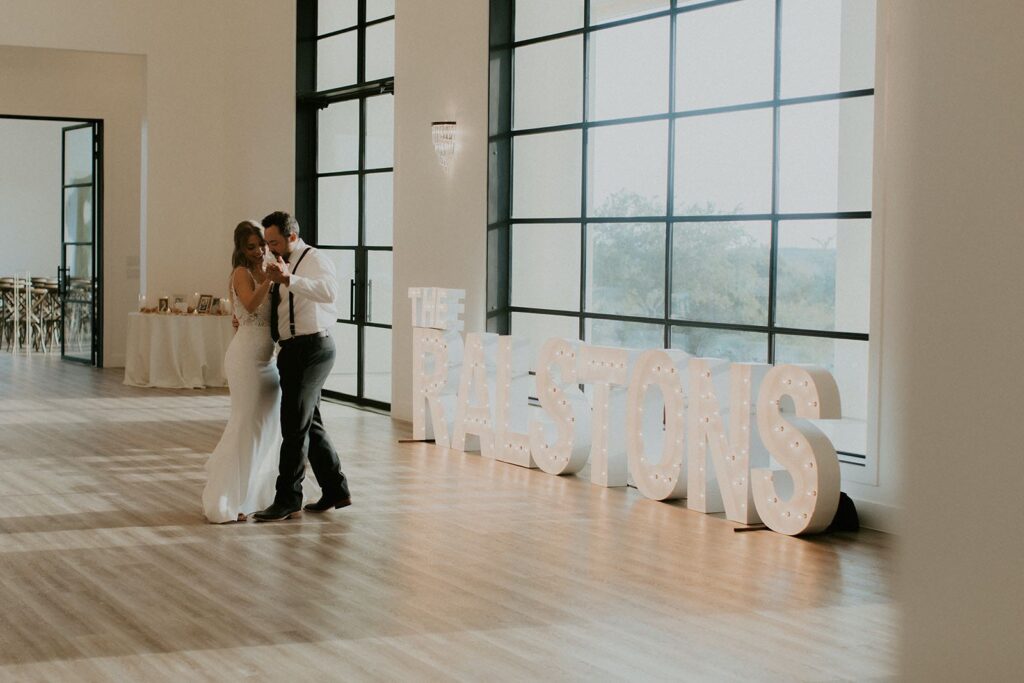 bride and groom first dance in front of marquee letters