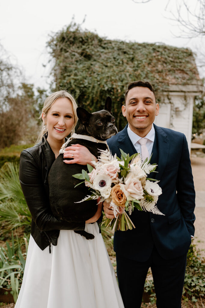 Bride holding small black dog on wedding day