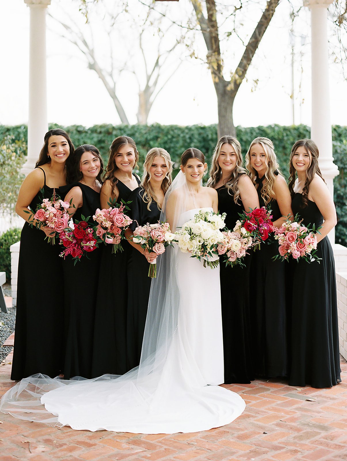 Bridesmaids in black dresses with pink ombre bouquets