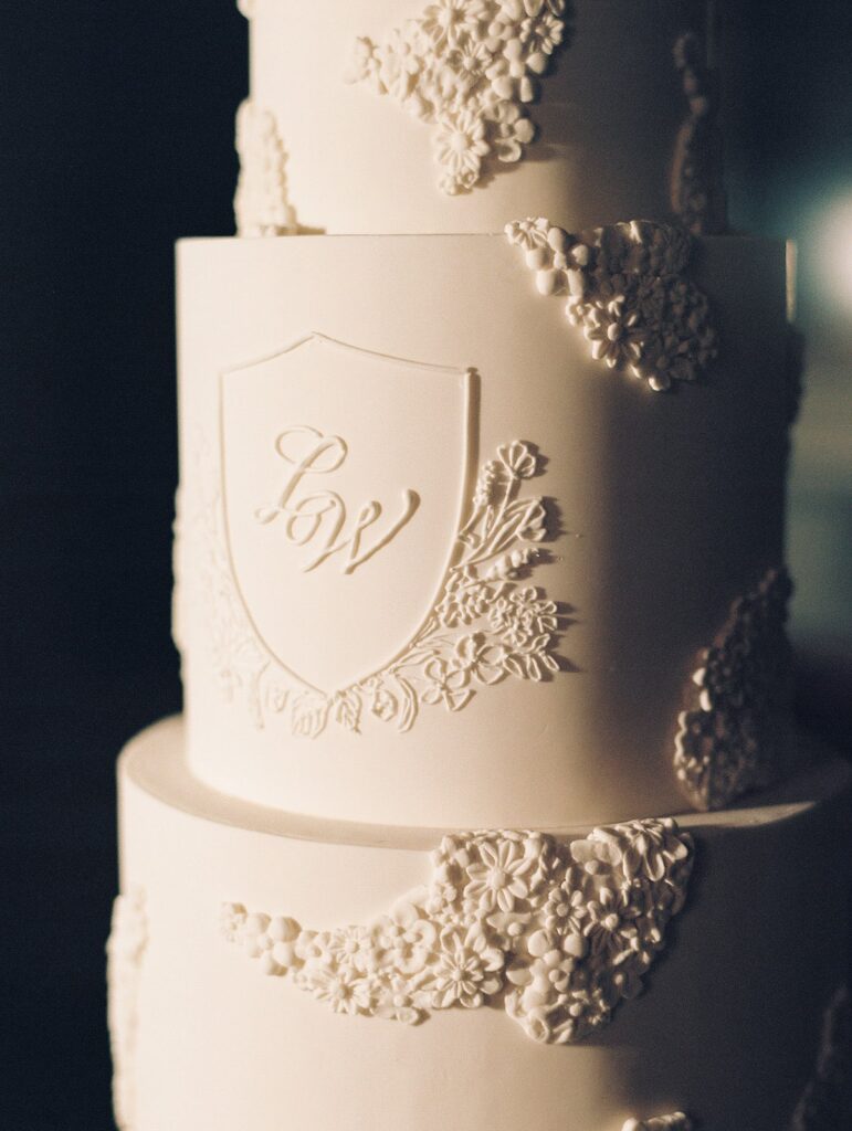 White wedding cake with custom crest and lace detailing
