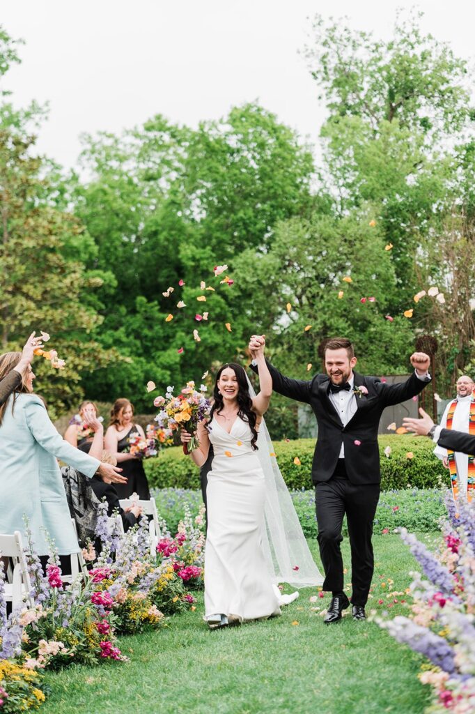 Bride and groom recessing while colorful petals are tossed