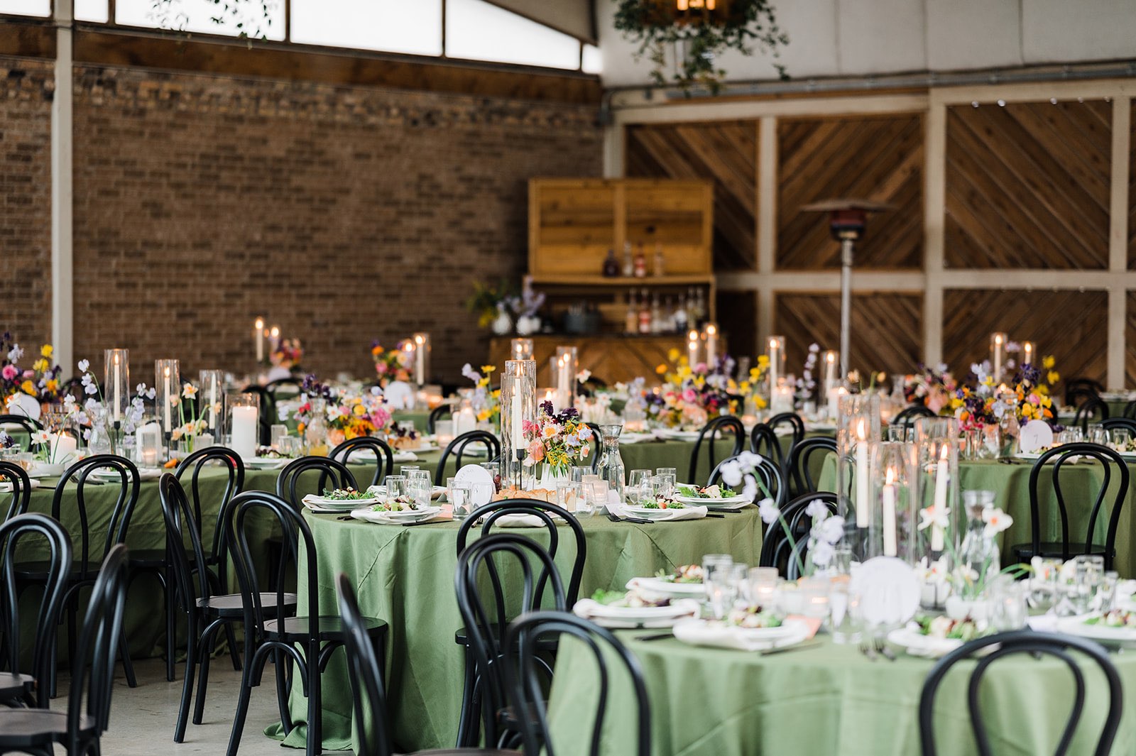 Colorful wedding reception with bold green linens and pink, orange and purple flowers
