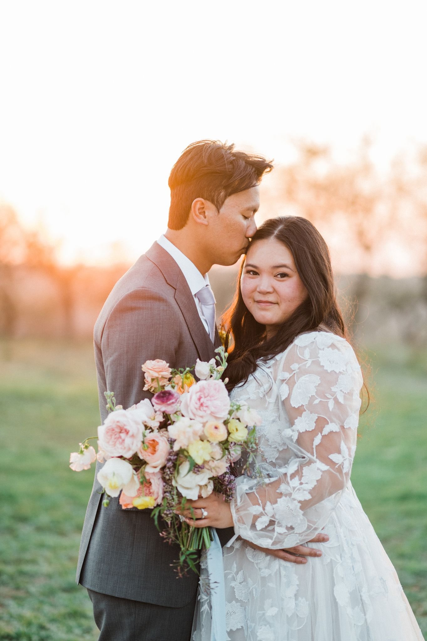 sunset photo of a bride and groom with a pastel bridal bouquet