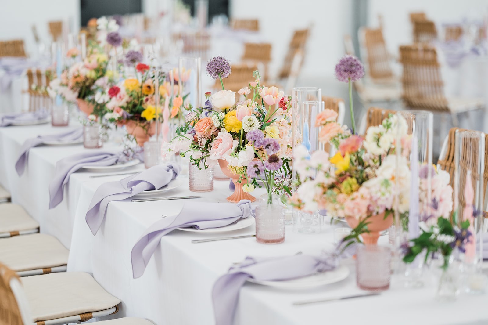 Colorful wedding head table with pastel flowers, lavender napkins and blush water goblets