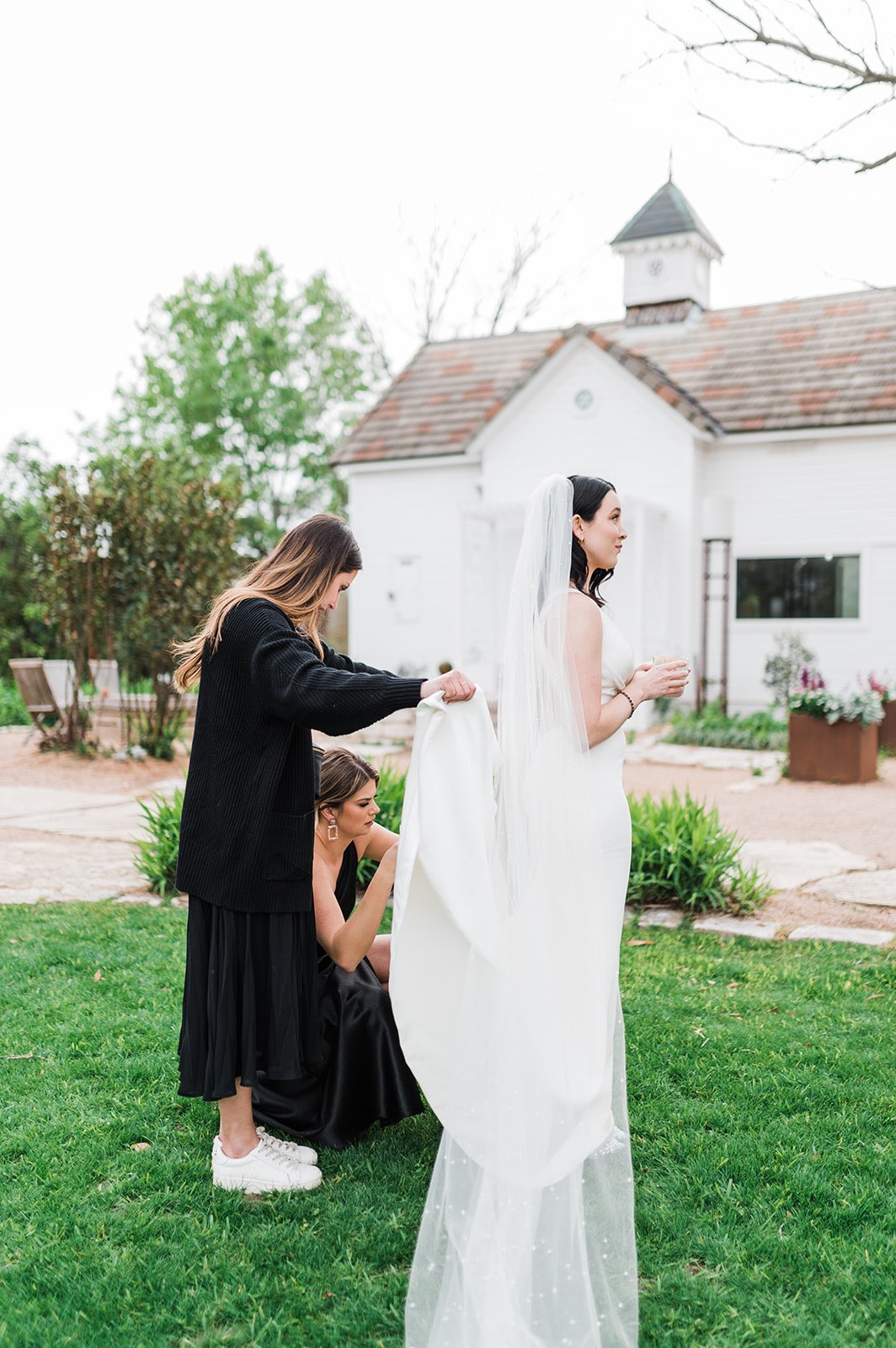 Wedding planner helping the maid of honor bustle the bride's dress