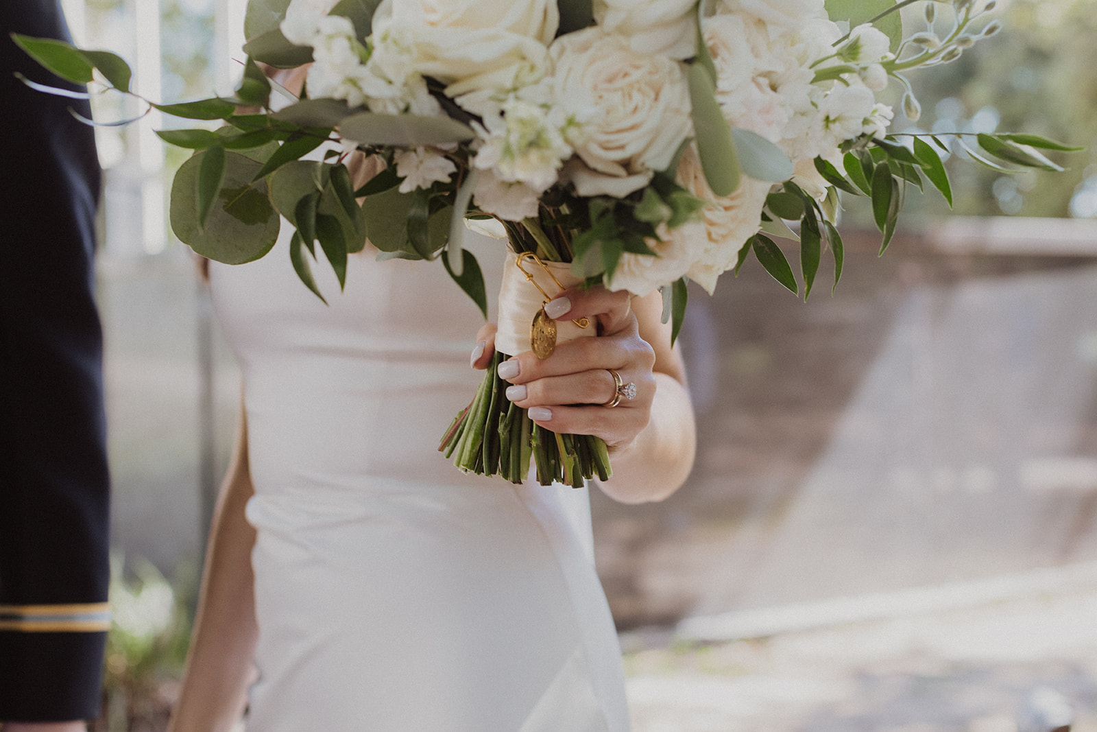 bride holding white bouquet with gold charm