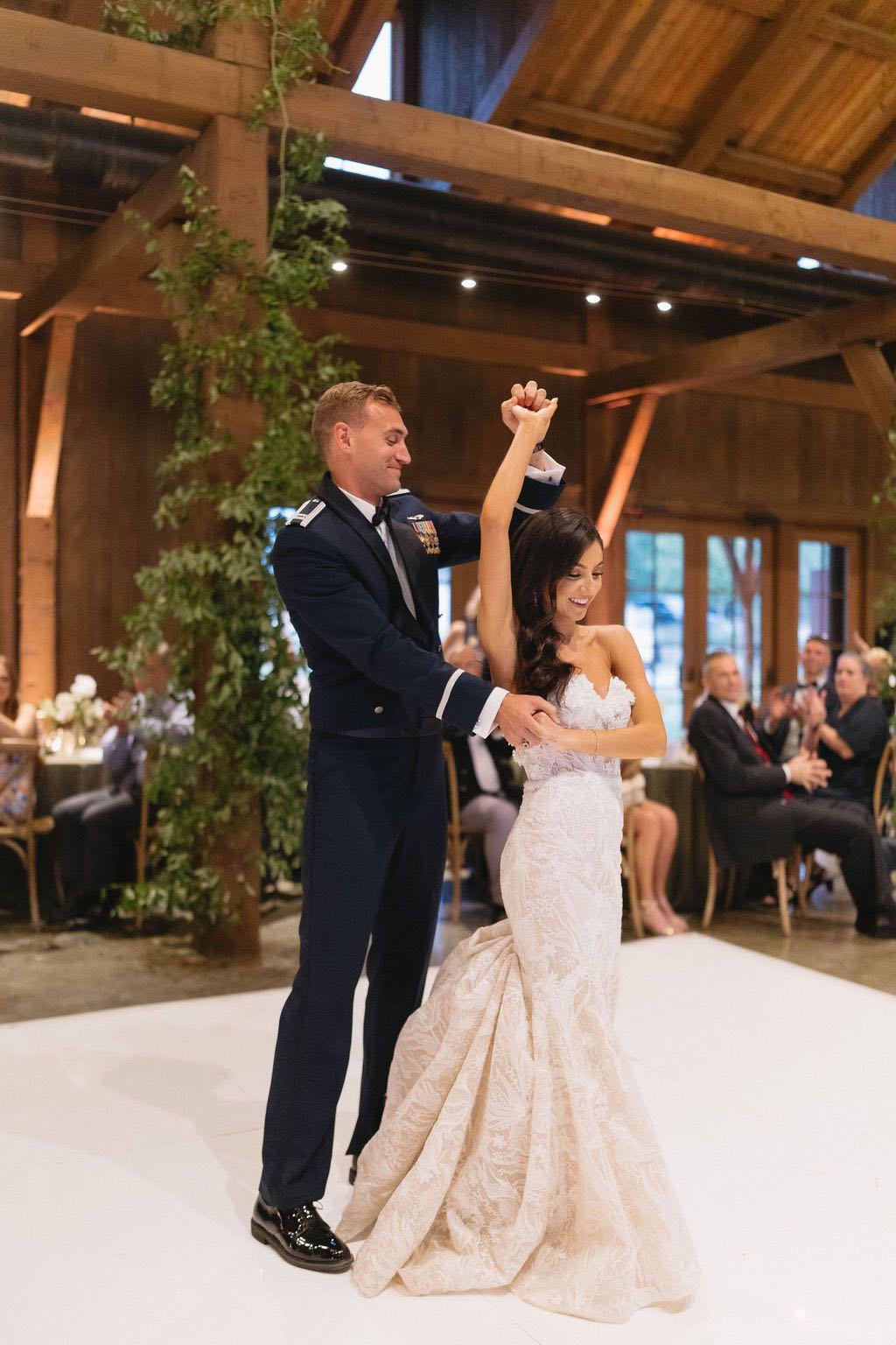 Bride and air force groom sharing their first dance on a white dance floor