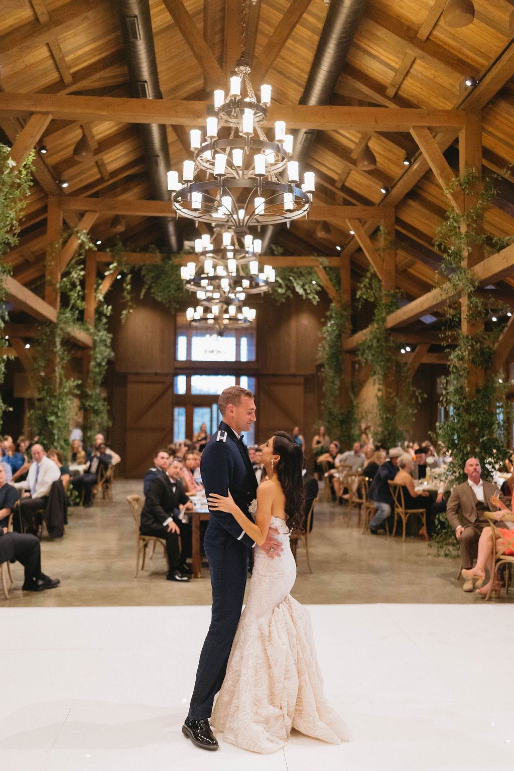 Bride and air force groom sharing their first dance on a white dance floor
