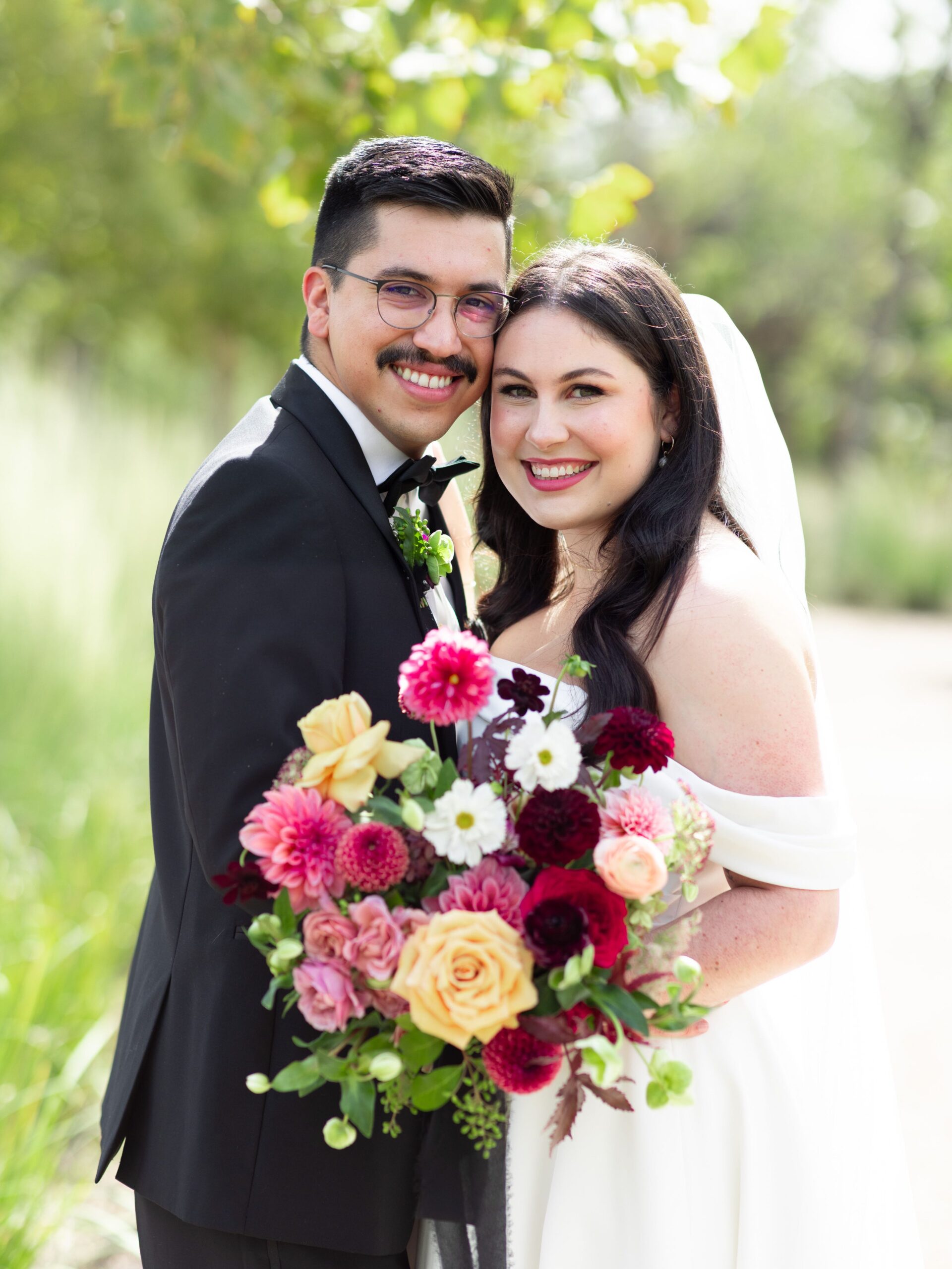 Bride and groom posting with burgundy and gold bridal bouquet