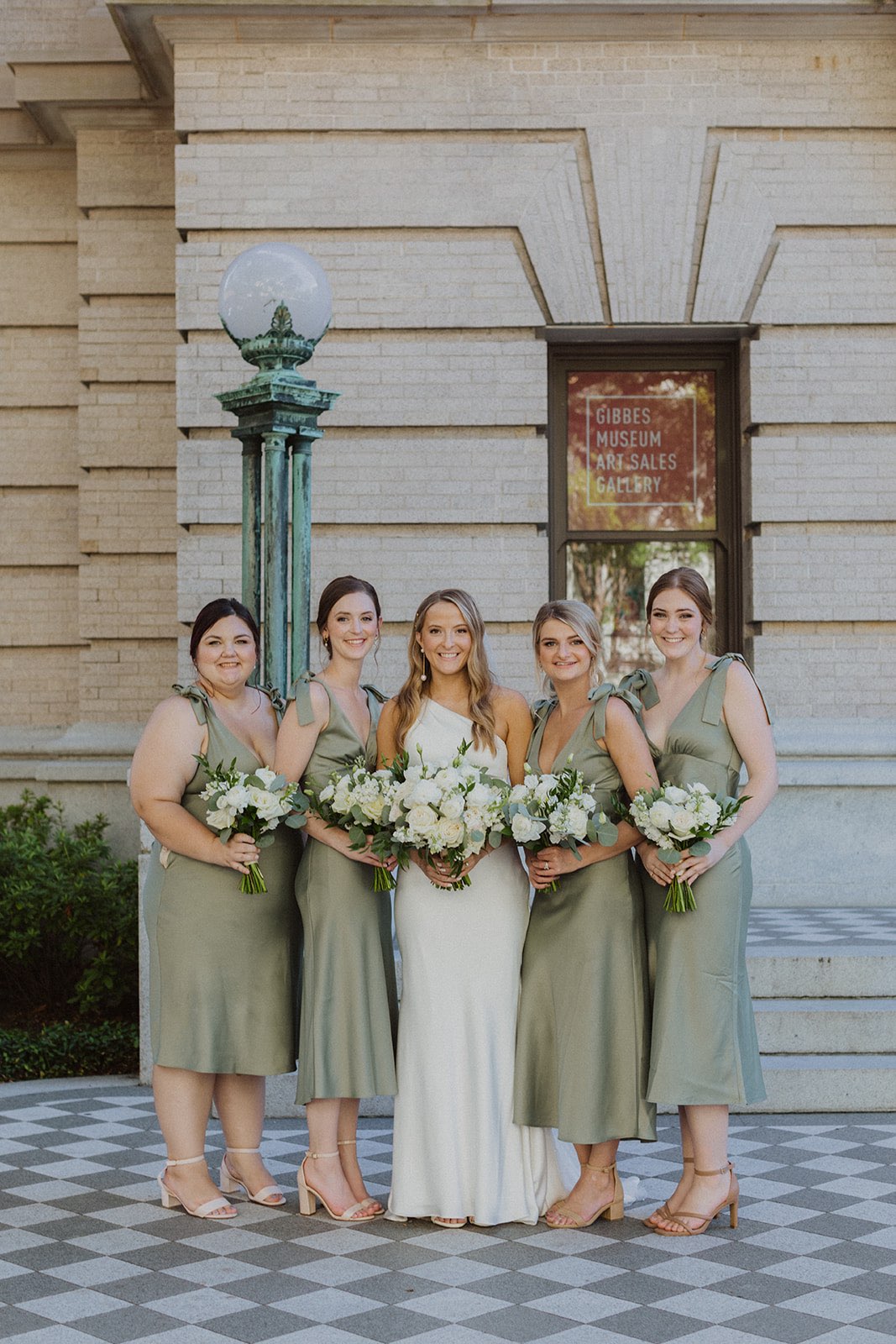 bride with bridesmaids in sage green midi dresses