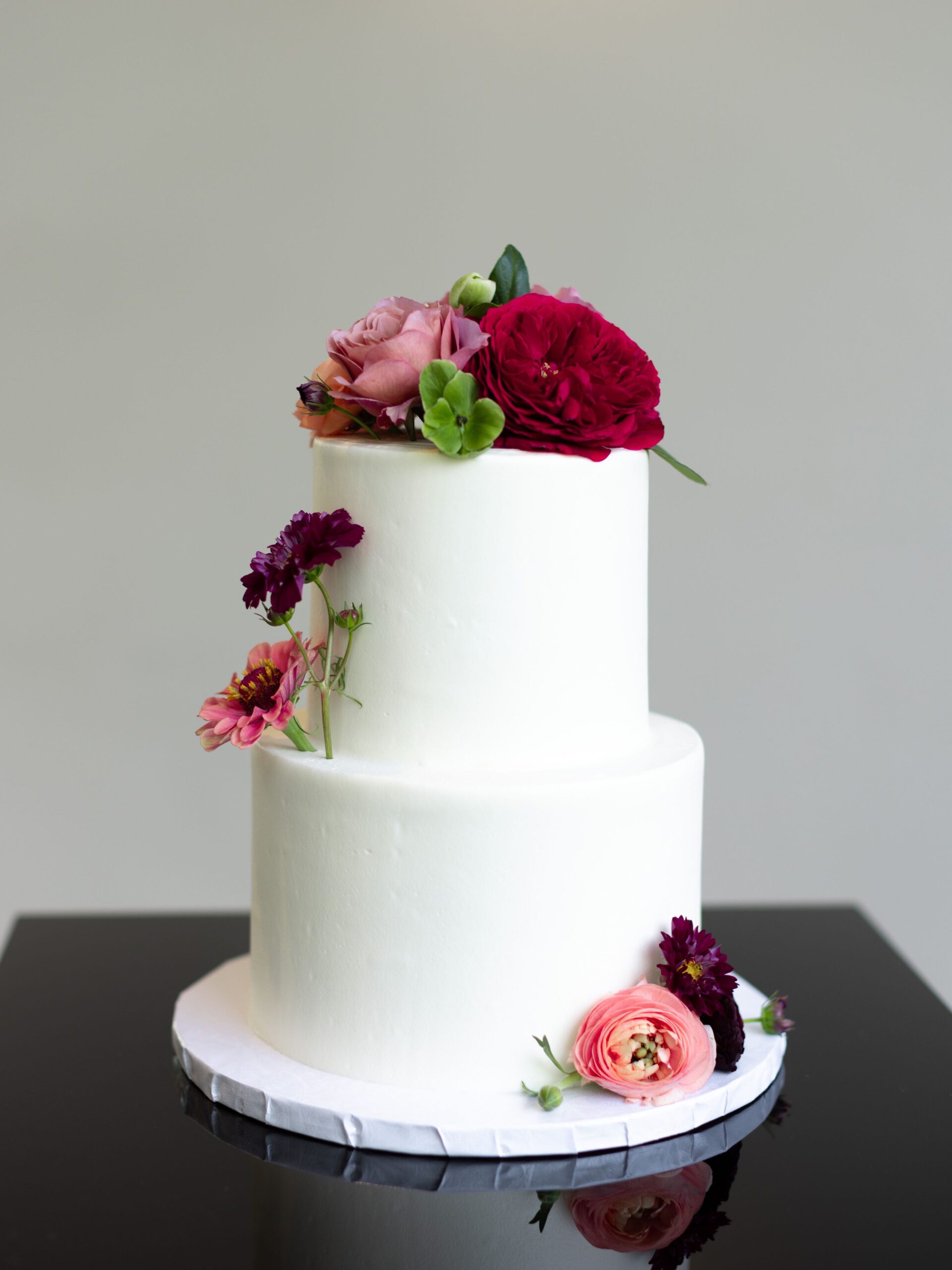 White wedding cake with plum and burgundy flowers