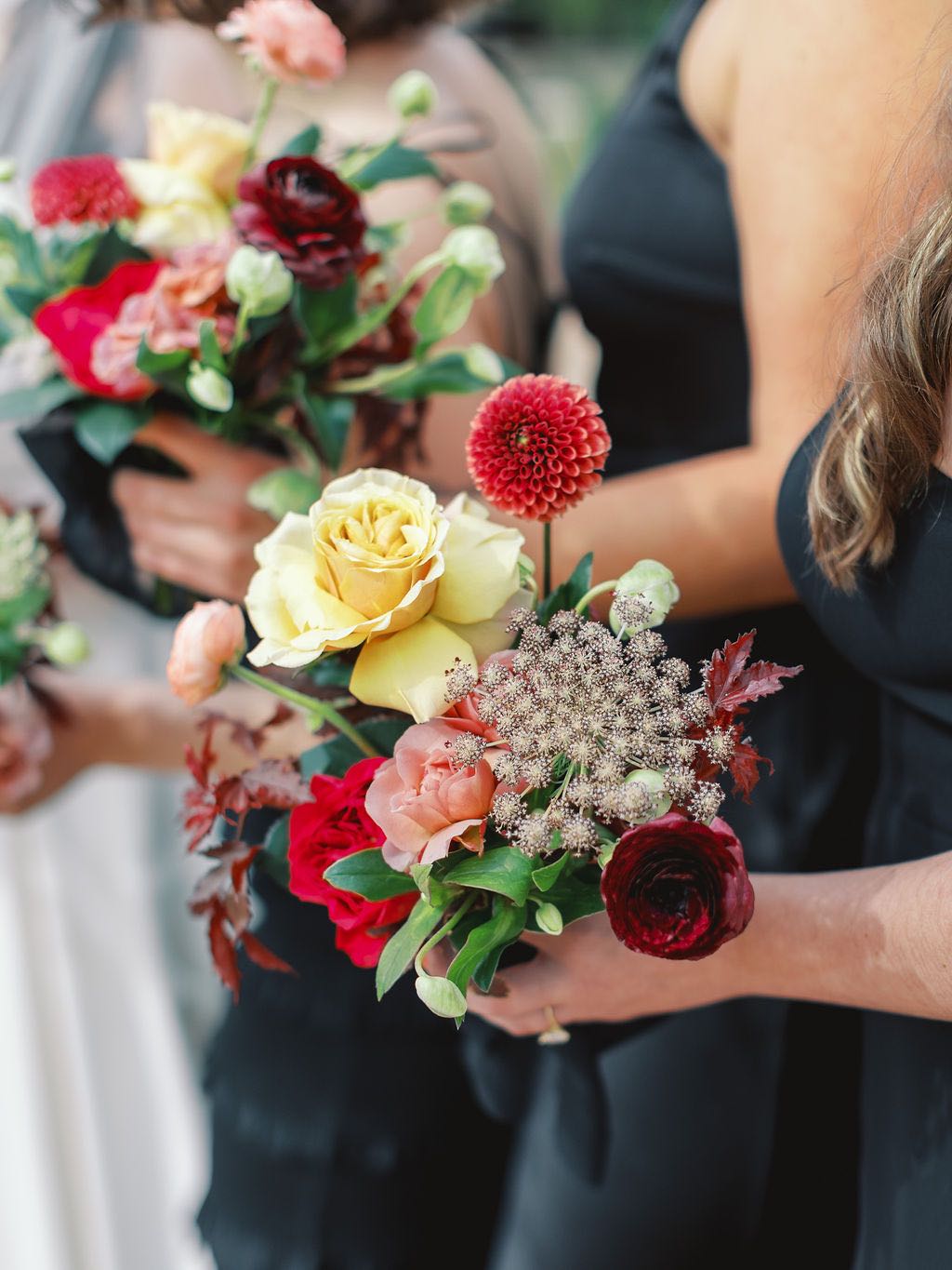 Small bridesmaid bouquets with buttery yellow, plum and maroon flowers