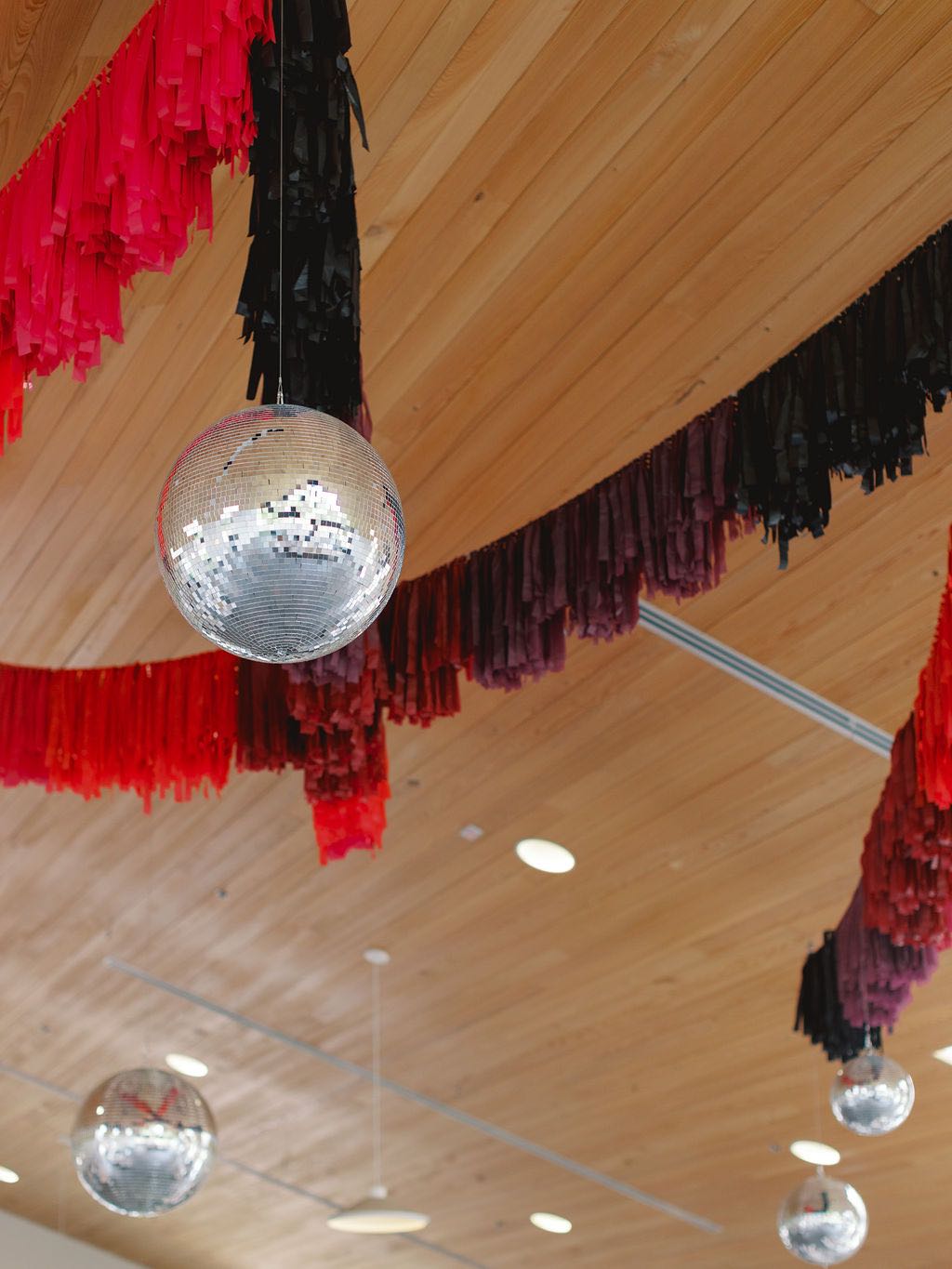 Plum and burgundy streamers hanging in reception venue with disco balls