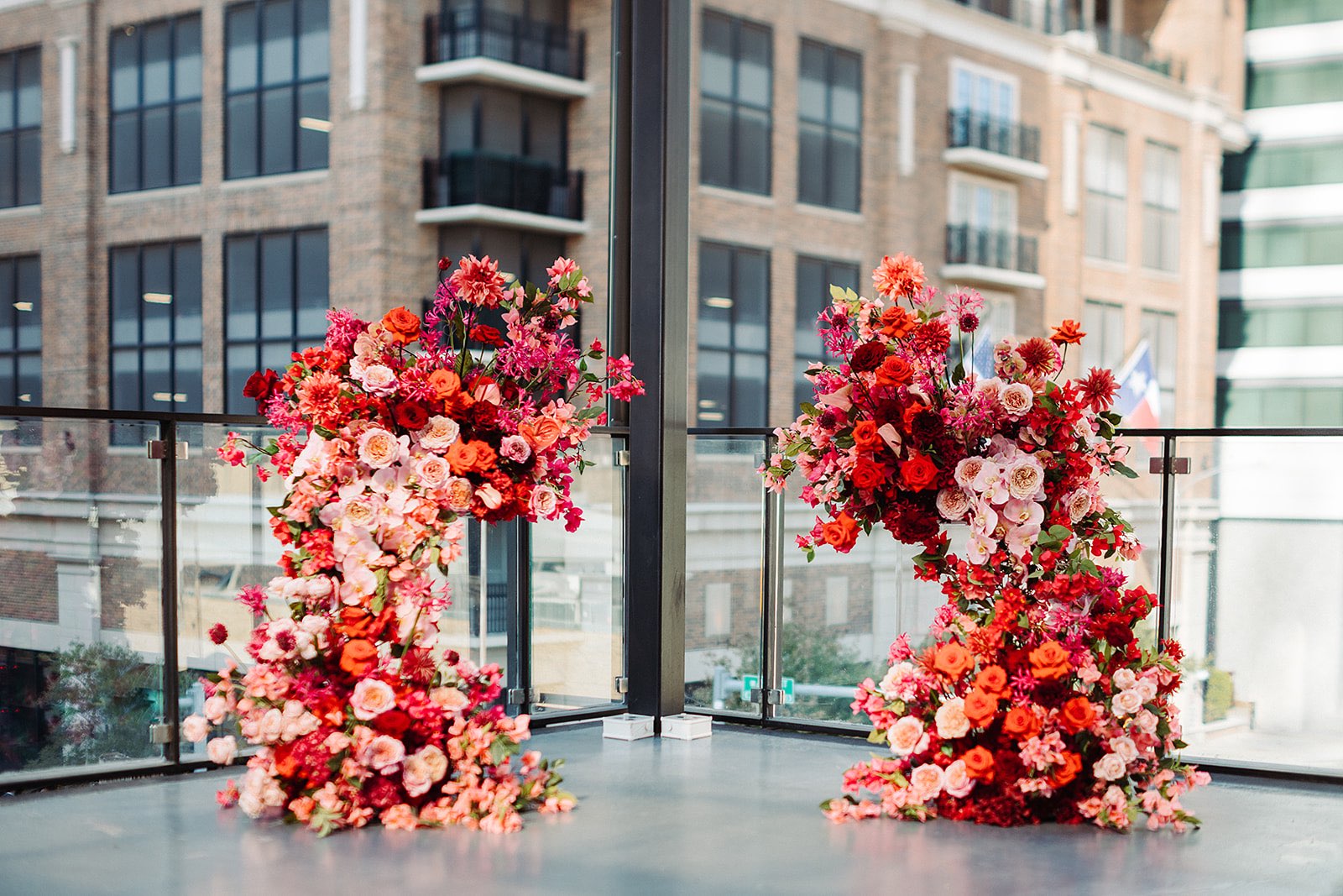 Asymmetrical wedding floral arch with mostly red and pink flowers, overlooking downtown Austin