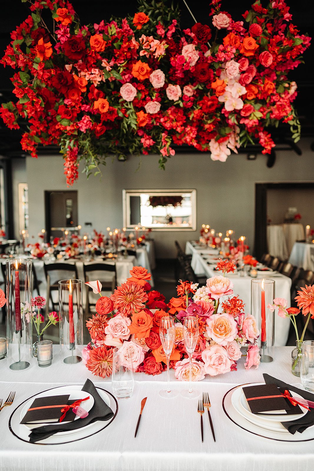 Bright red and pink flowers on sweetheart table with hanging flowers above