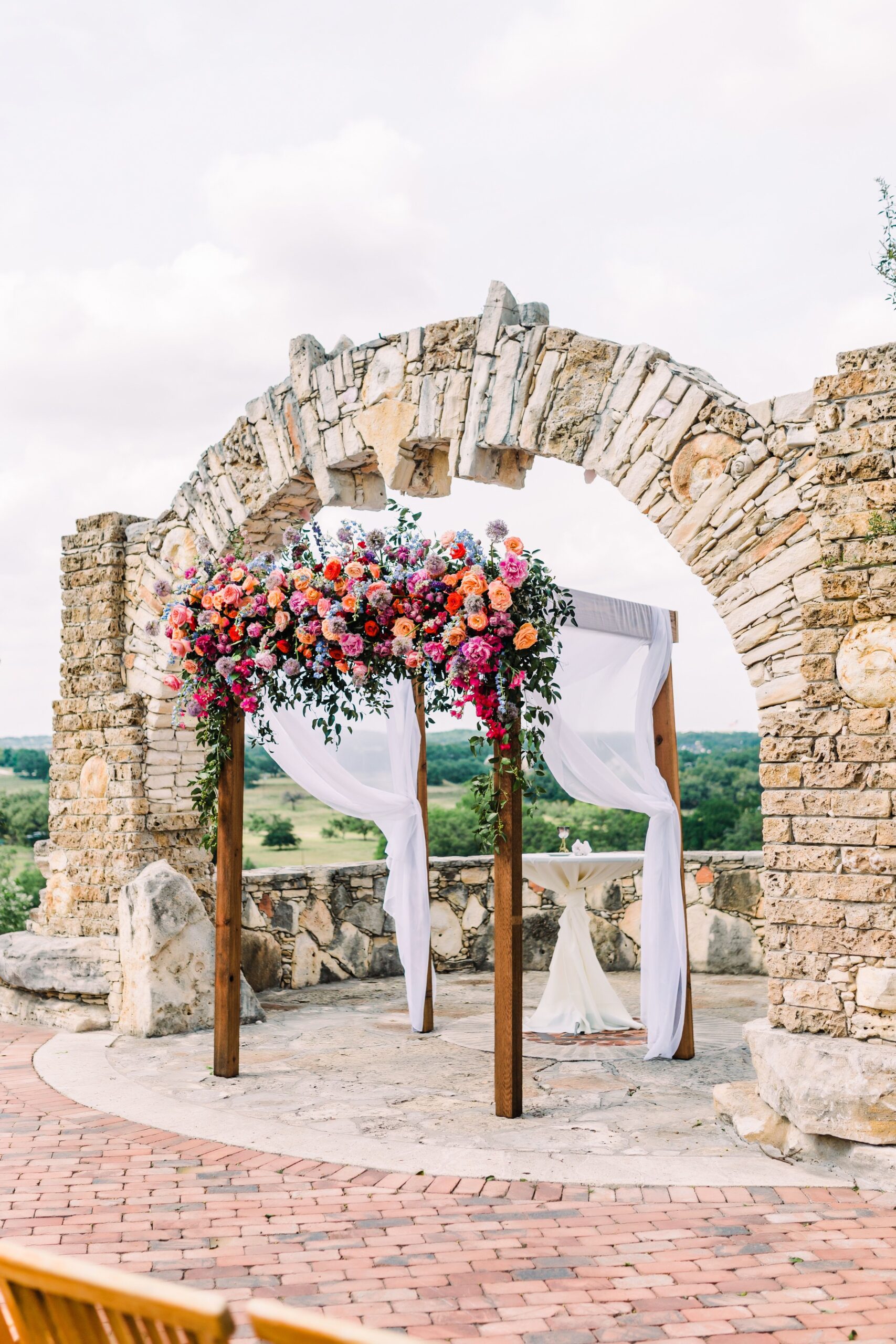 colorful flowers on wooden chuppah at camp lucy, a wedding venue in austin texas
