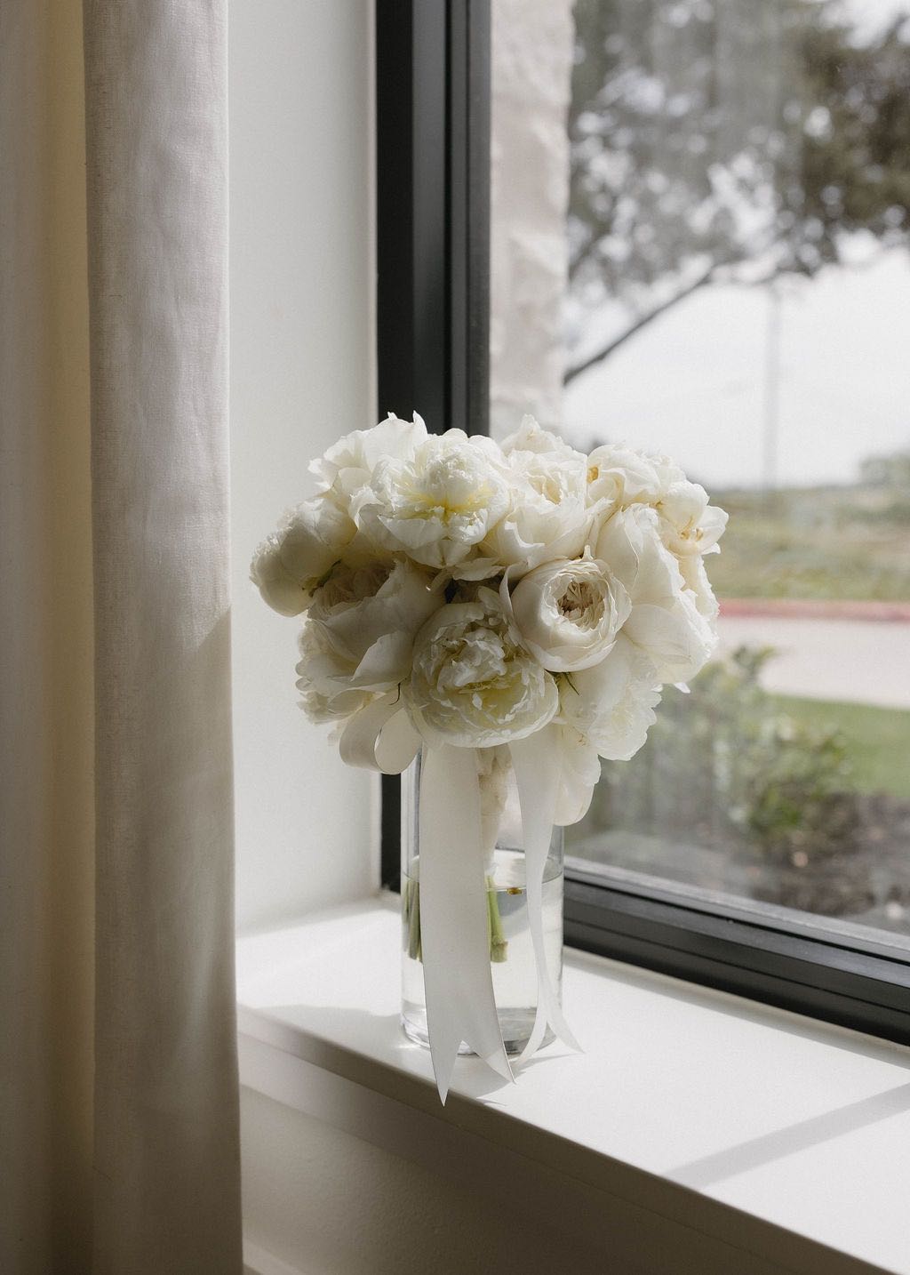 White bridal bouquet with white roses and white peonies, tied with silk ribbon