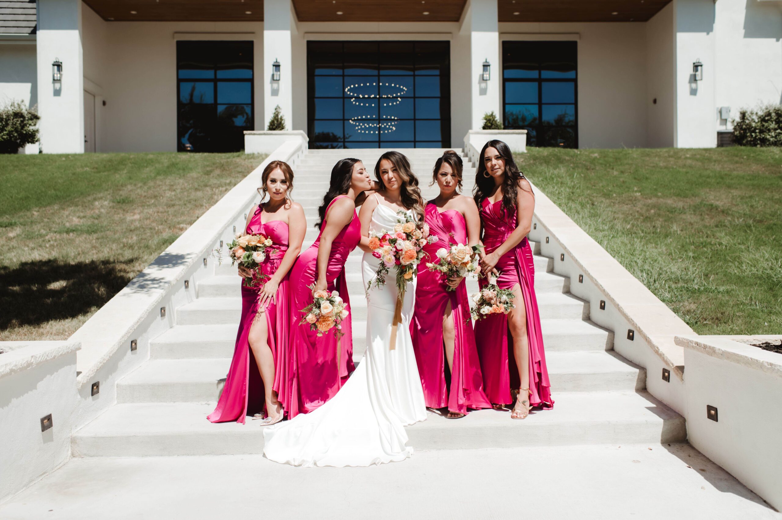 Bride and bridesmaids wearing hot pink dresses on the grand staircase at The Arlo