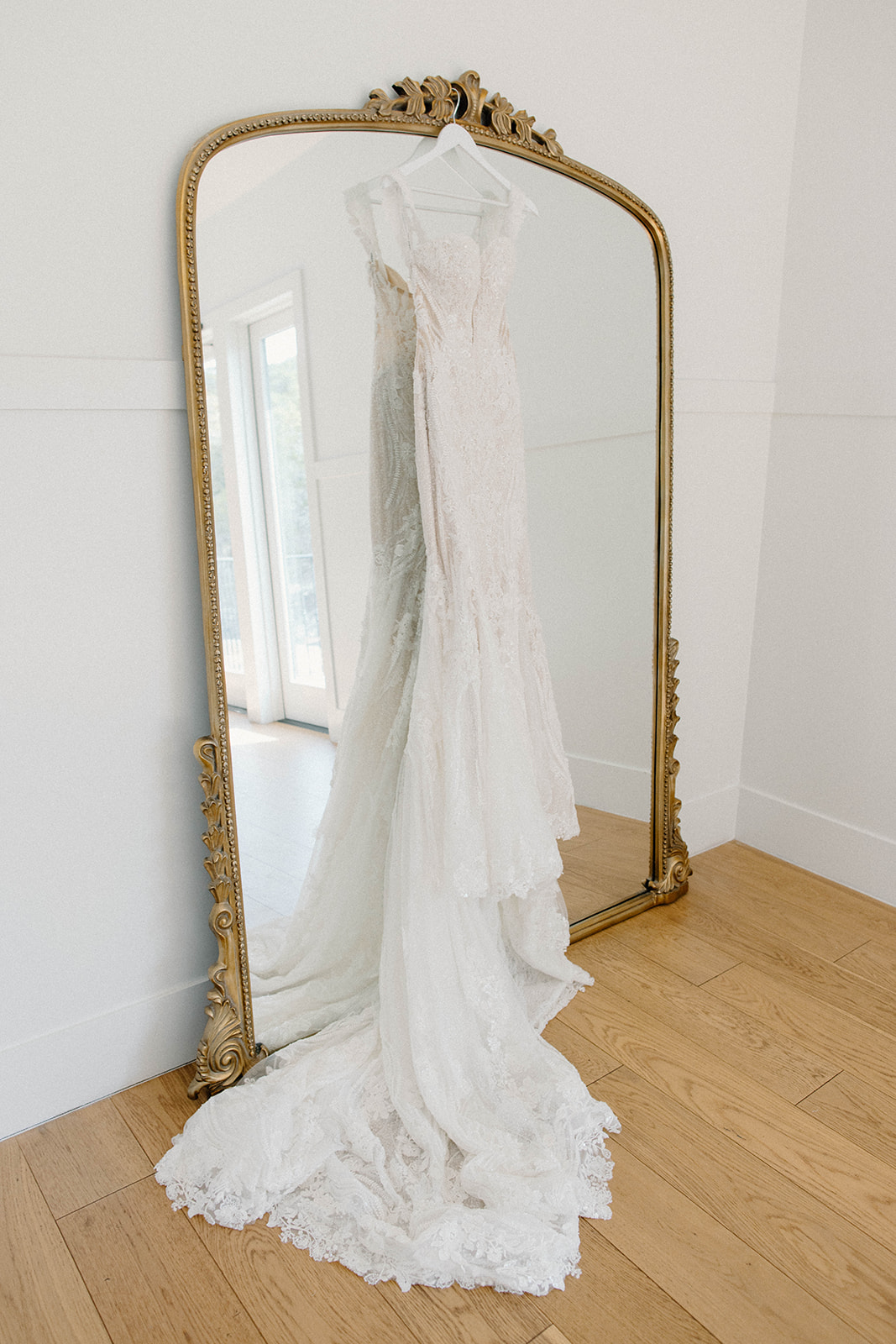 Lace wedding gown hanging on gold mirror