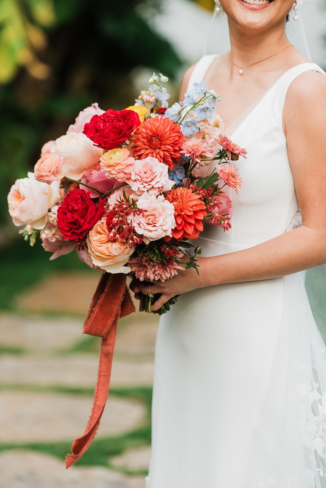 Bridal bouquet with red, coral, peach, blush and blue flowers 