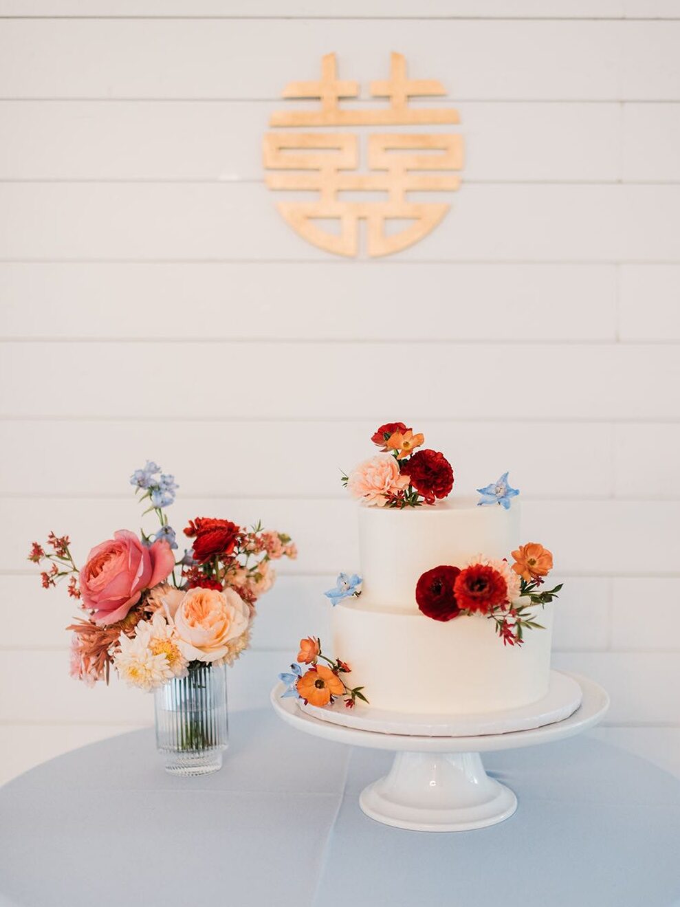 Garden wedding cake with white frosting and red, orange and blue flowers